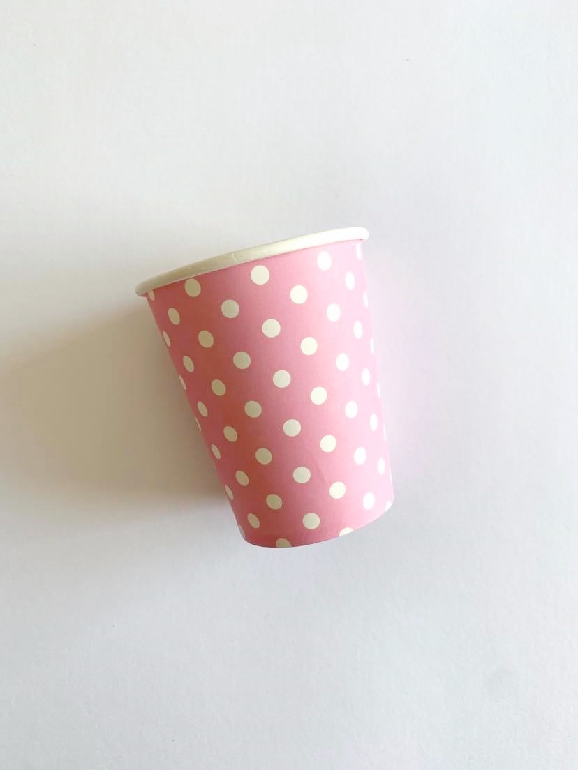 Copo de papel rosa com bolinhas brancas sobre fundo branco