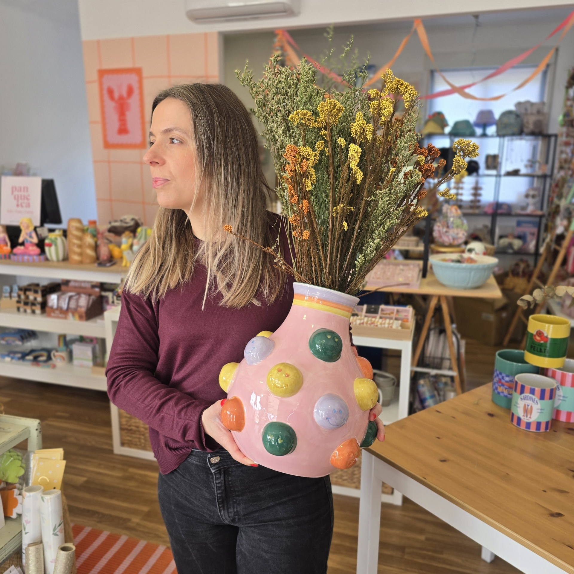 Vaso de cerâmica cor-de-rosa com bolhas coloridas e flores secas numa loja