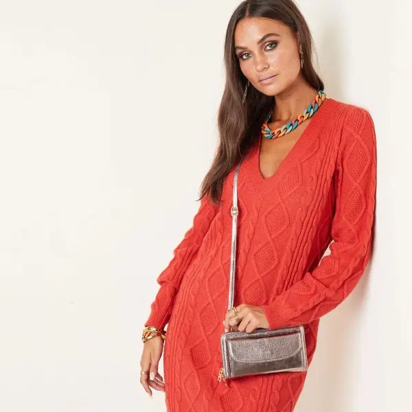 Mulher com vestido vermelho de malha e mala prateada