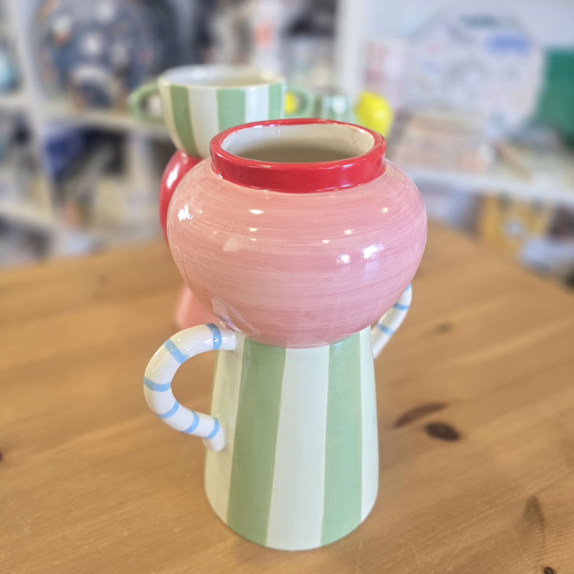 Jarro de cerâmica pintado à mão com riscas verdes, brancas, rosa e vermelhas