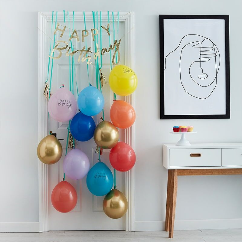Decoração de aniversário com balões coloridos pendurados numa porta branca