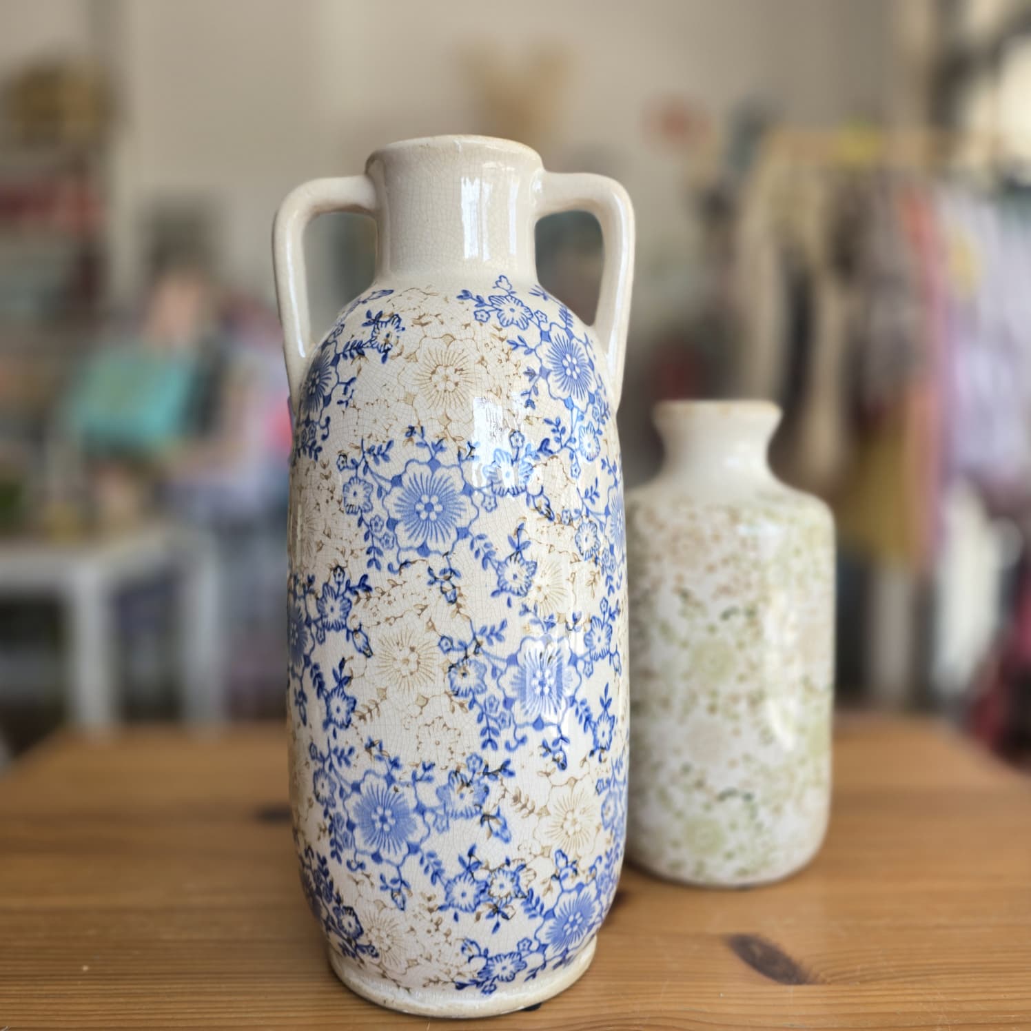Dois vasos cerâmicos decorados com padrões florais sobre uma mesa de madeira.