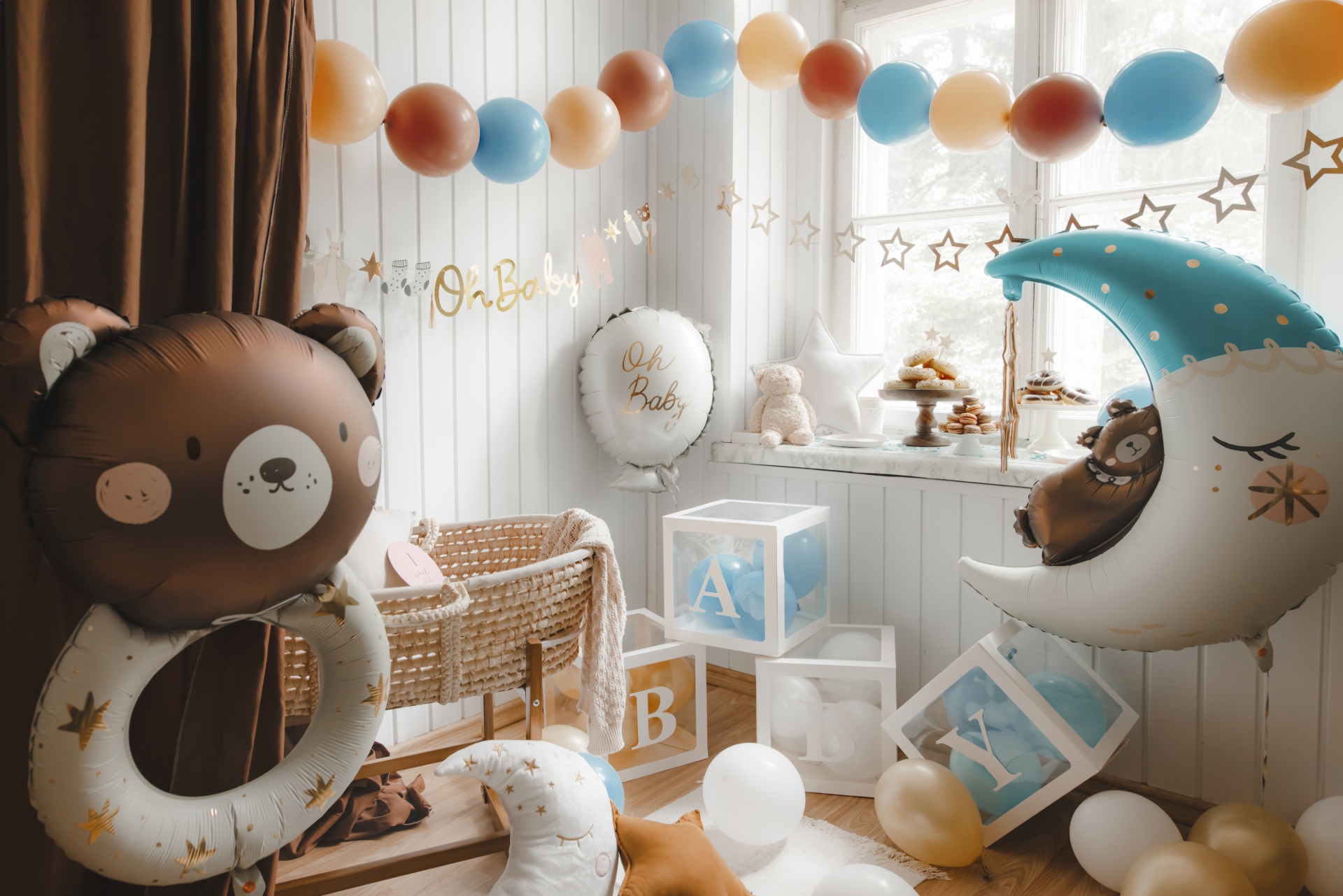 Decoração para festa de bebé com balões coloridos, berço e cubos decorativos