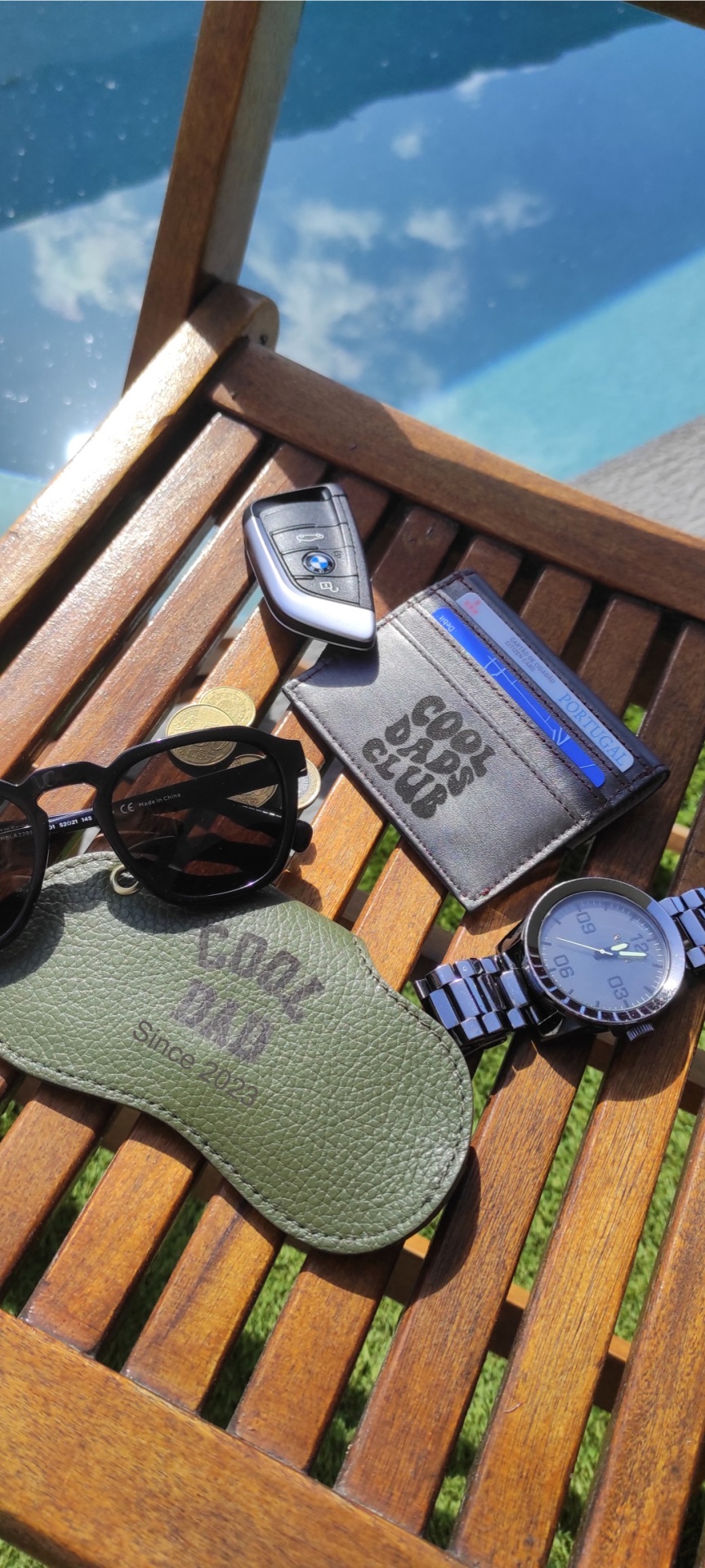 Acessórios masculinos sobre superfície de madeira com céu refletido