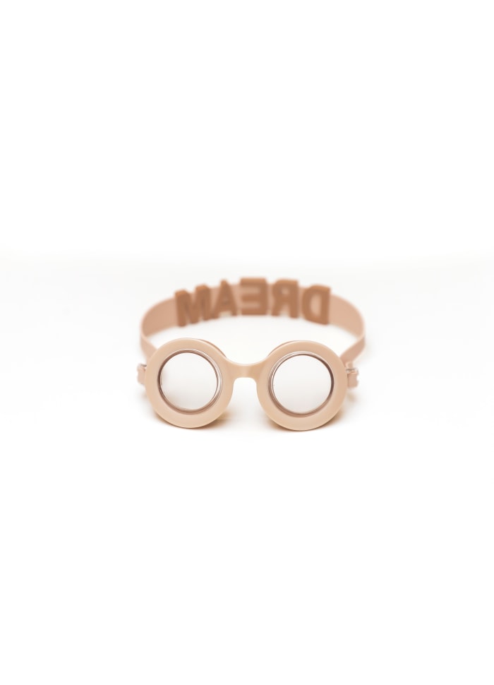 Óculos de proteção rosa claro com lentes redondas espelhadas e fita traseira com a palavra DREAM