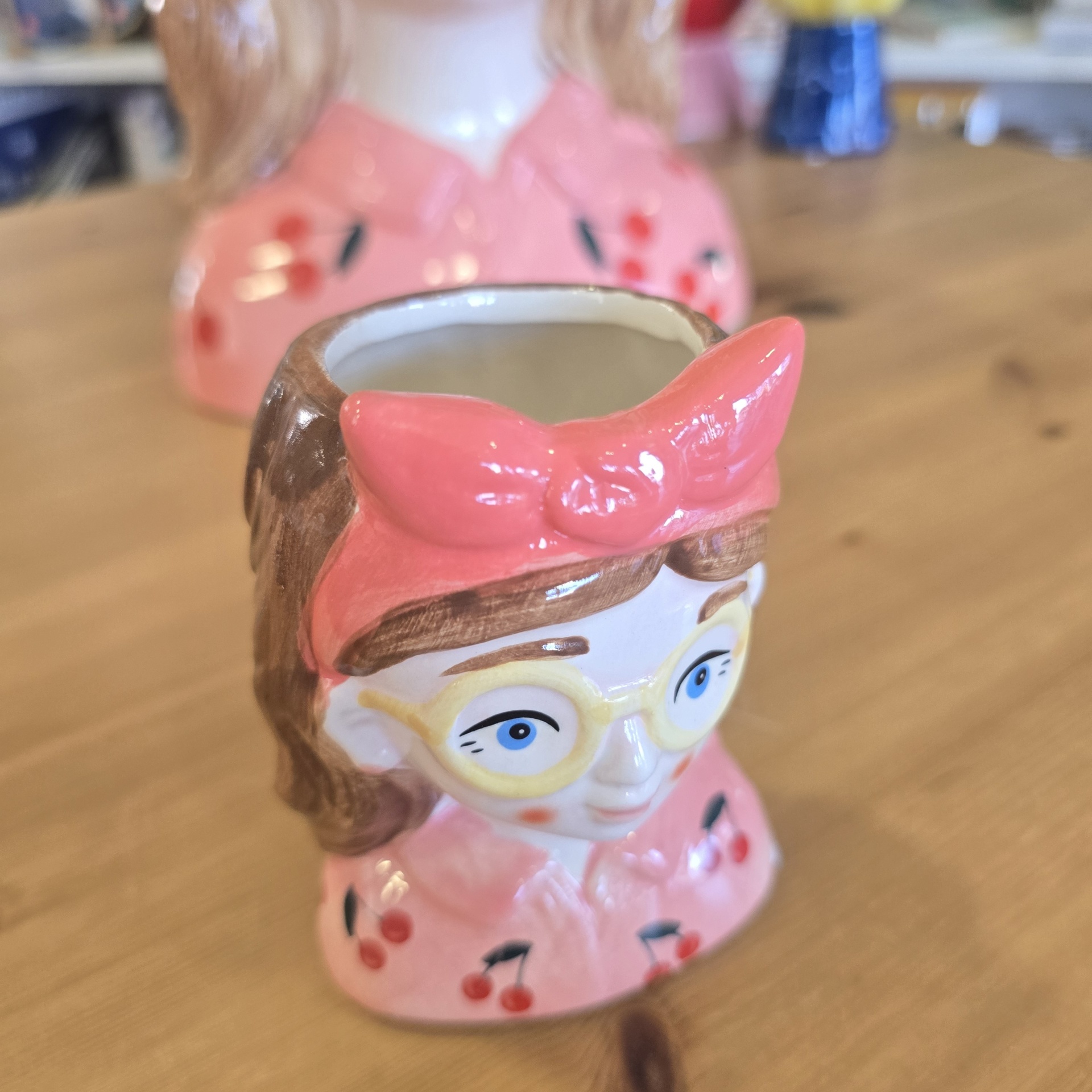 Vaso de cerâmica em forma de cabeça feminina com óculos e lenço cor-de-rosa