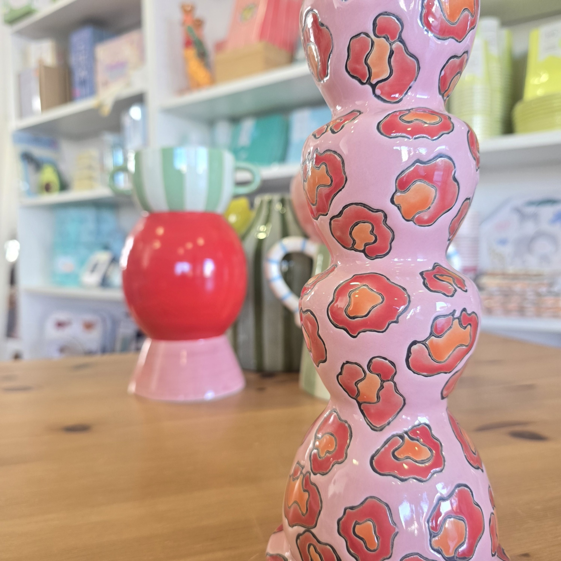 Vasos decorativos em cerâmica com padrões coloridos sobre mesa de madeira.