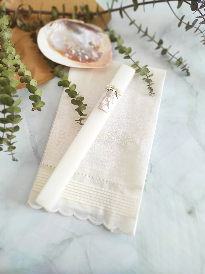 Guardanapo branco com vela decorada e ramos de eucalipto sobre superfície de mármore