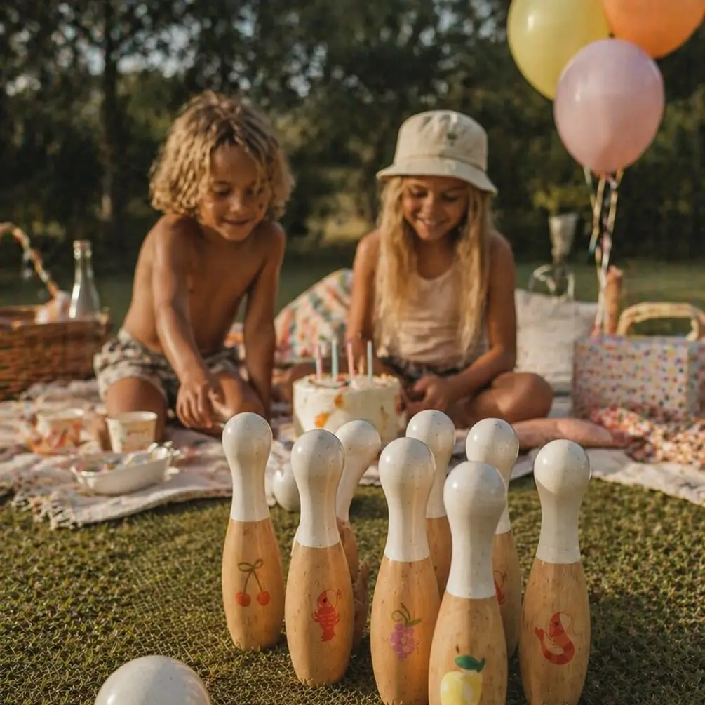 Pinos de bowling de madeira com desenhos coloridos e criança a brincar num piquenique