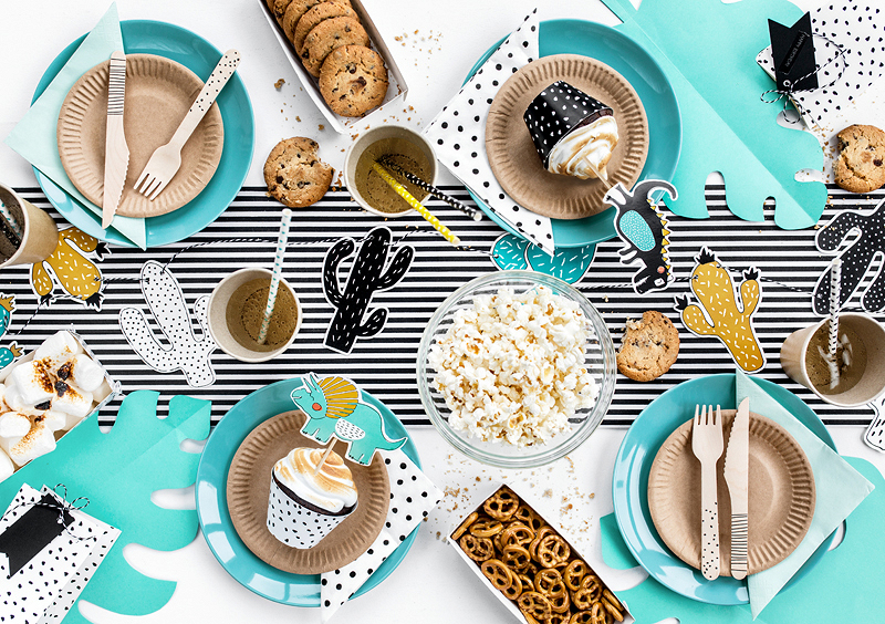 Mesa de festa com utensílios de papel e madeira, pipocas, bolachas, pretzels e toalha de riscas