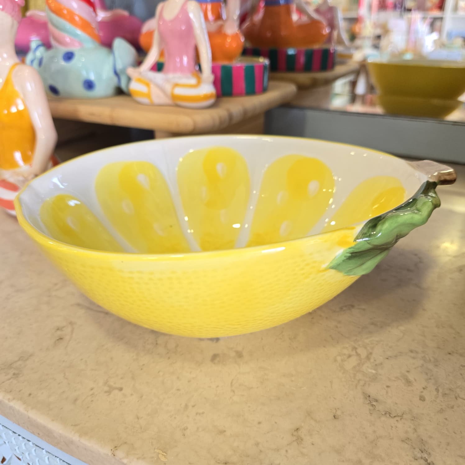 Taça cerâmica amarela com decoração de gomos de limão e folha verde na borda