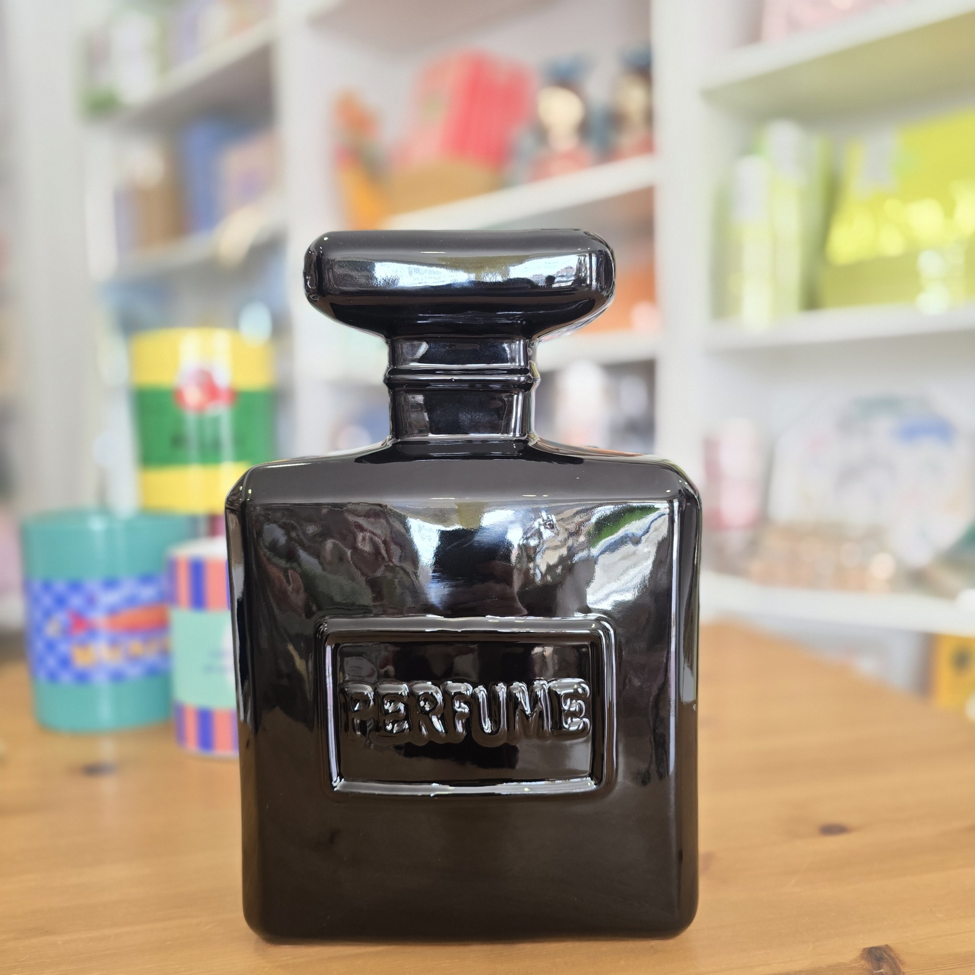 Garrafa de perfume preta brilhante com tampa grande e palavra PERFUME em relevo