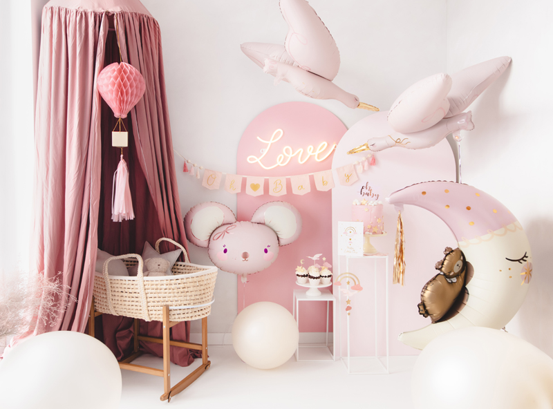 Quarto de bebé decorado com balões, móbile e figuras cor-de-rosa e brancas