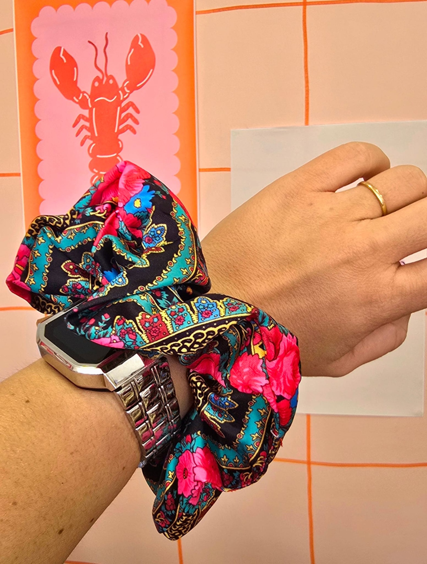 Relógio com bracelete metálica prateada e scrunchie floral colorido no pulso