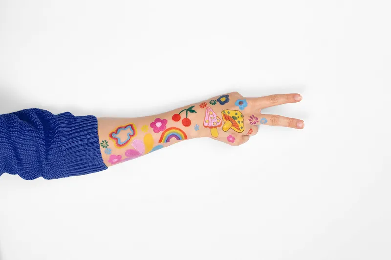 Braço com tatuagens temporárias coloridas sobre manga azul