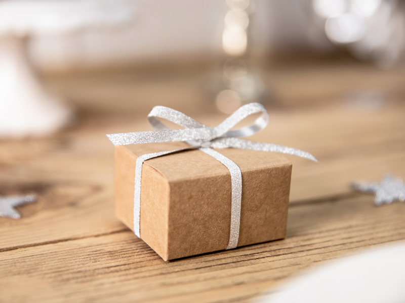 Pequena caixa de presente castanha com fita prateada sobre mesa de madeira