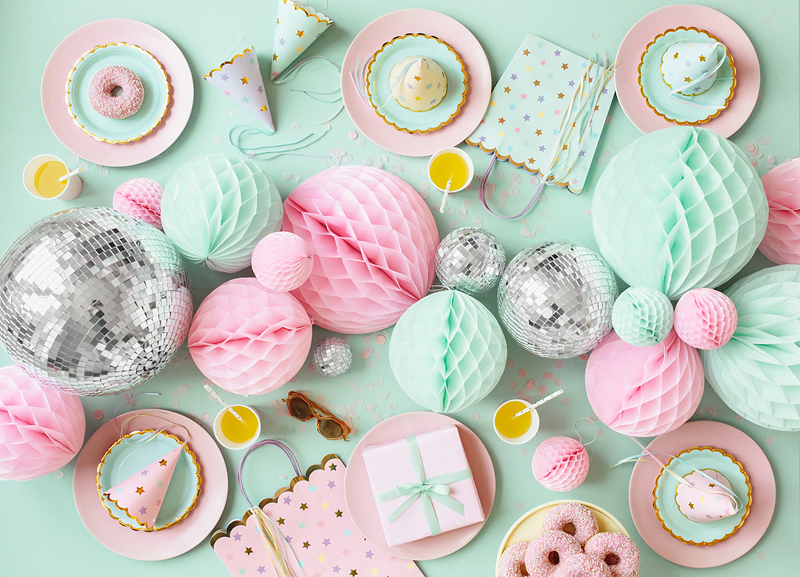 Mesa decorada para festa com doces, balões de papel coloridos e caixas de presente em tons pastel