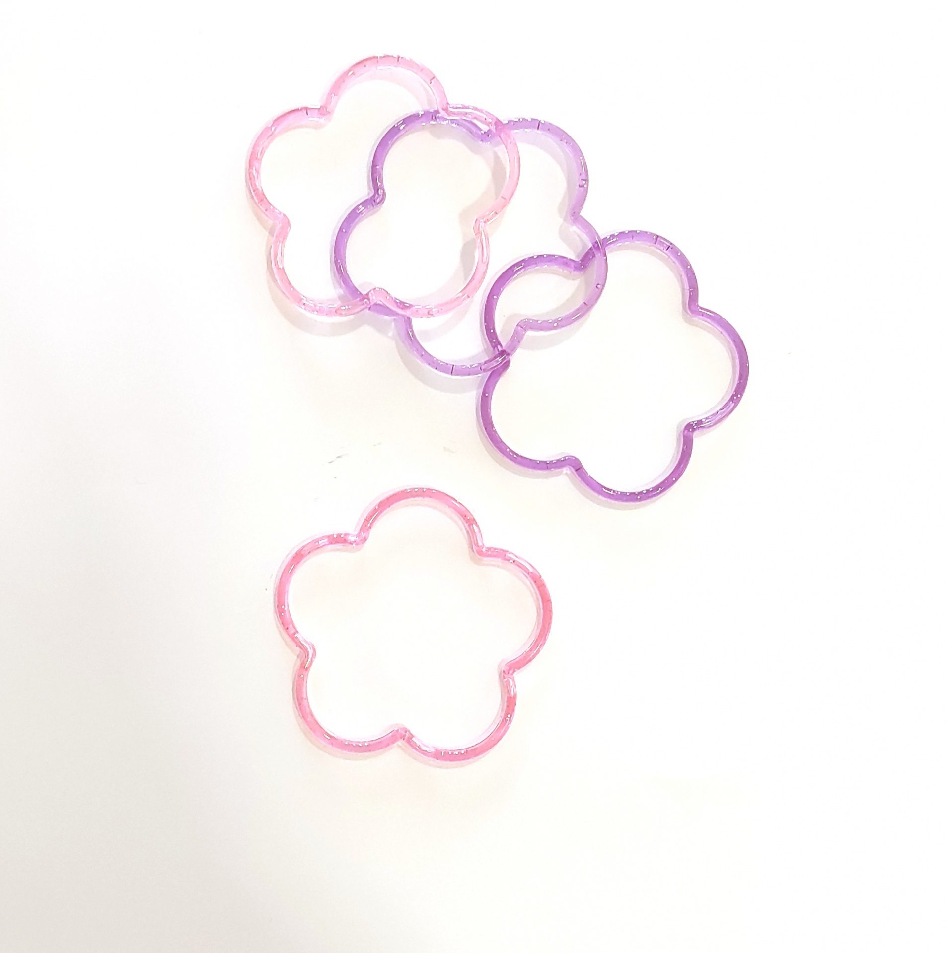 Elásticos para cabelo em forma de flor, cores rosa e roxo, fundo branco.