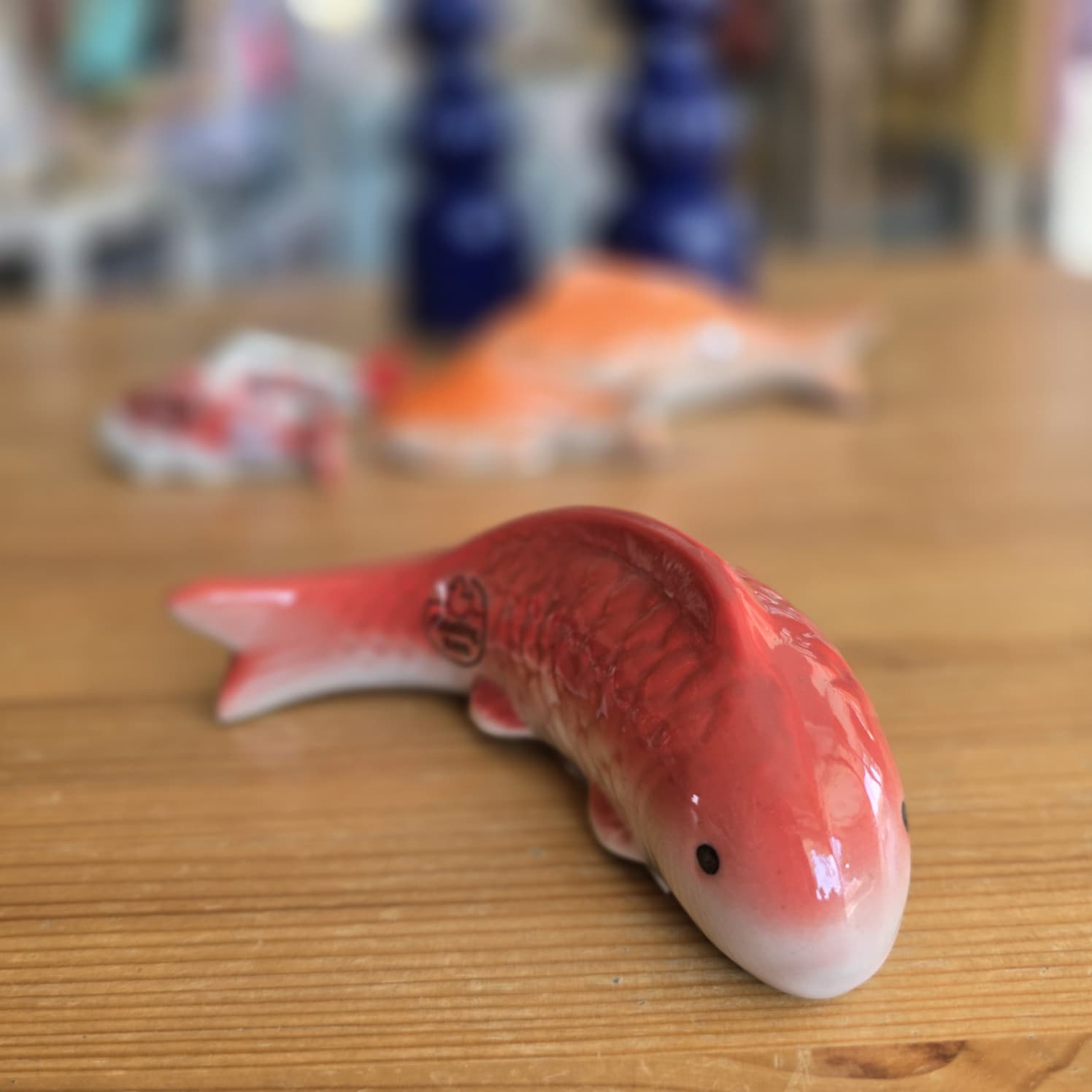 Figura de cerâmica de peixe vermelho sobre mesa de madeira