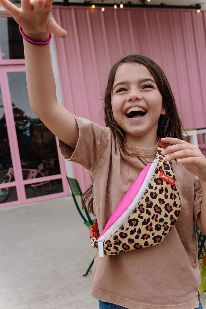 Menina sorridente com mala de cintura com padrão animal print e interior rosa