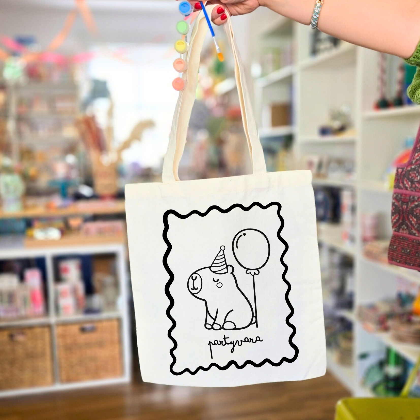Mala de pano branca com desenho preto de um urso com chapéu de festa e balão