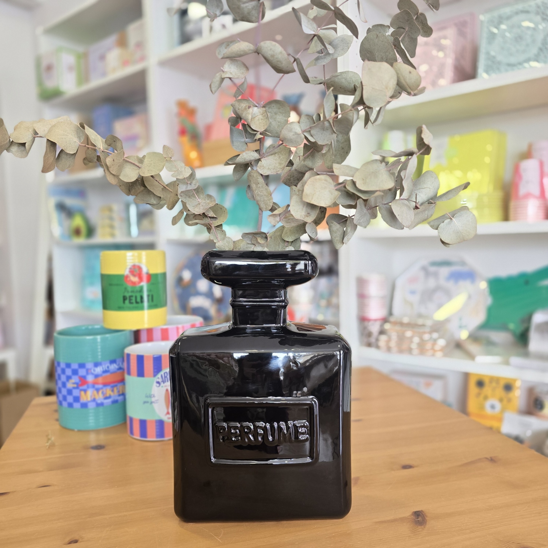 Frasco preto decorativo com ramos secos sobre mesa de madeira