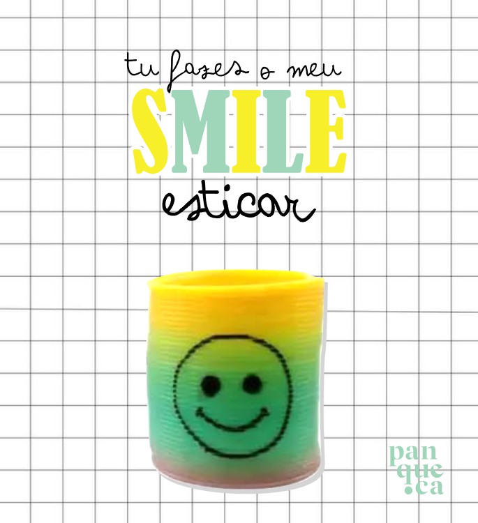 Suporte para vela colorido com sorriso e texto motivacional em fundo quadriculado.