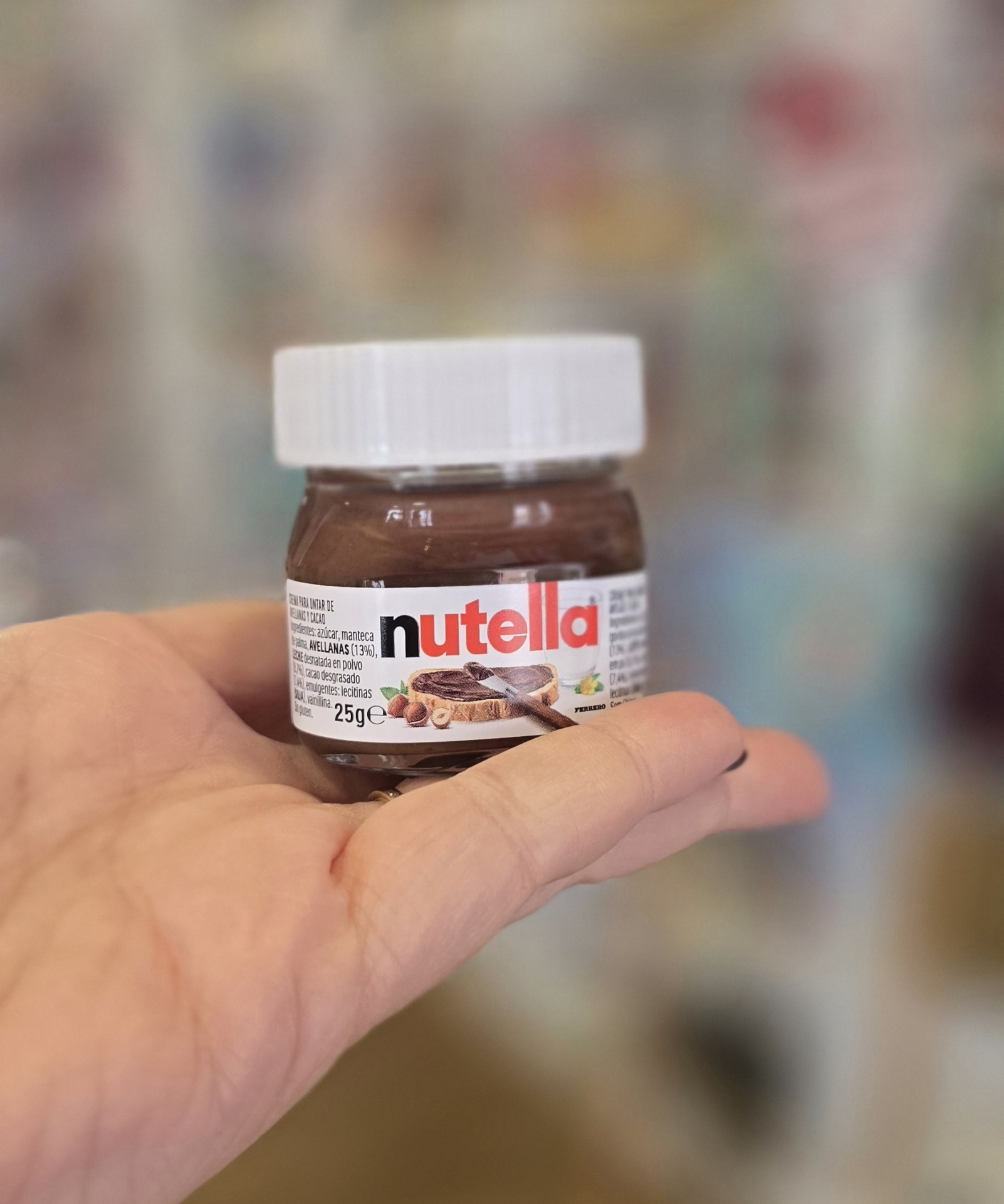 Frasco pequeno de Nutella 25g com rótulo e tampa branca segurado na mão
