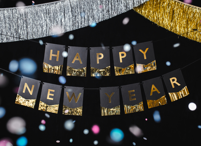 Decoração de festa com letras douradas HAPPY NEW YEAR em fundo preto com franjas douradas e prateadas