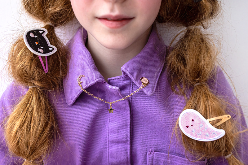 Camisola lilás com gola e corrente dourada em menina com tranças e presilhas de cabelo