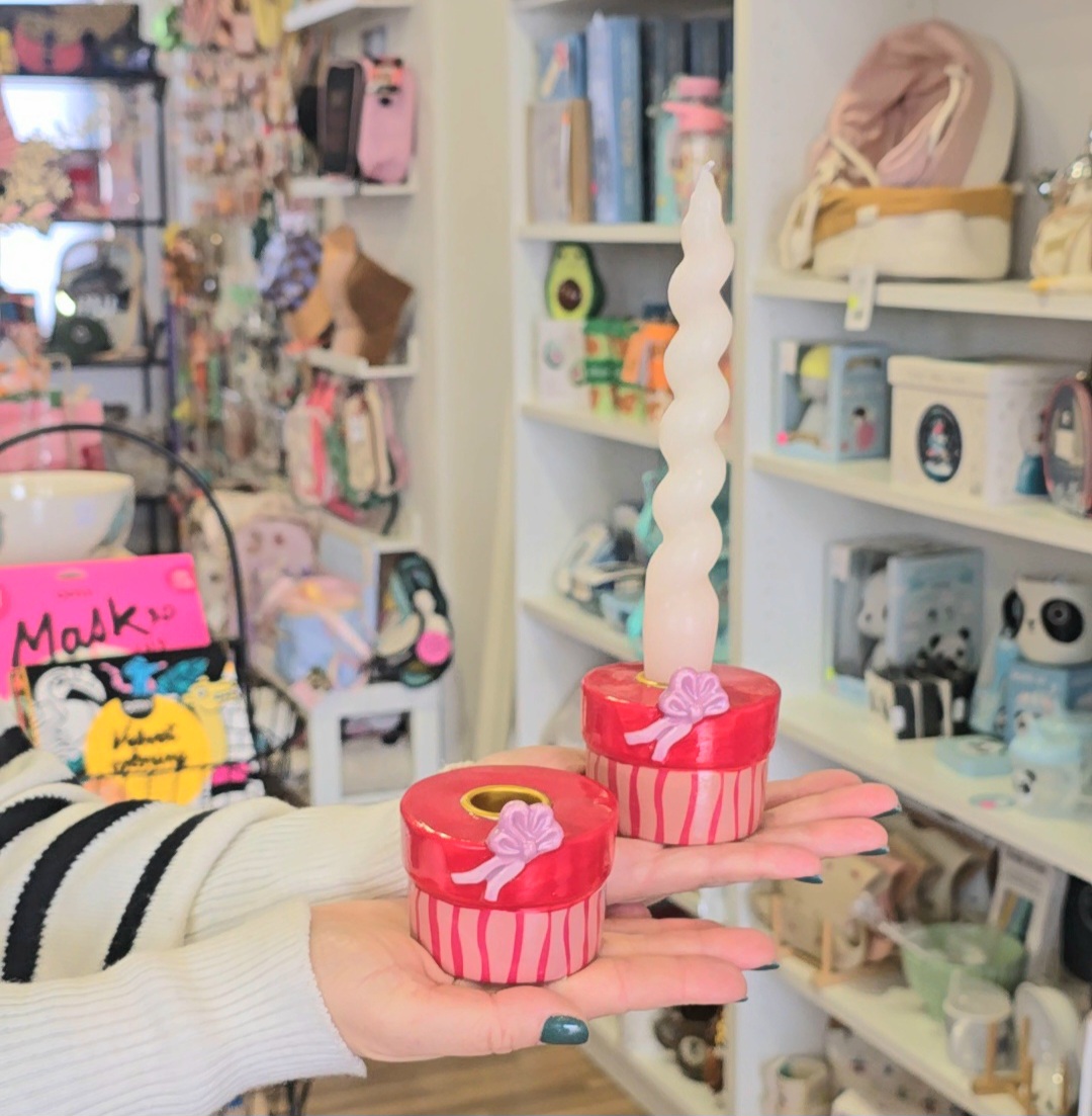 Bases de vela decorativas vermelhas e rosas com vela branca torcida numa loja