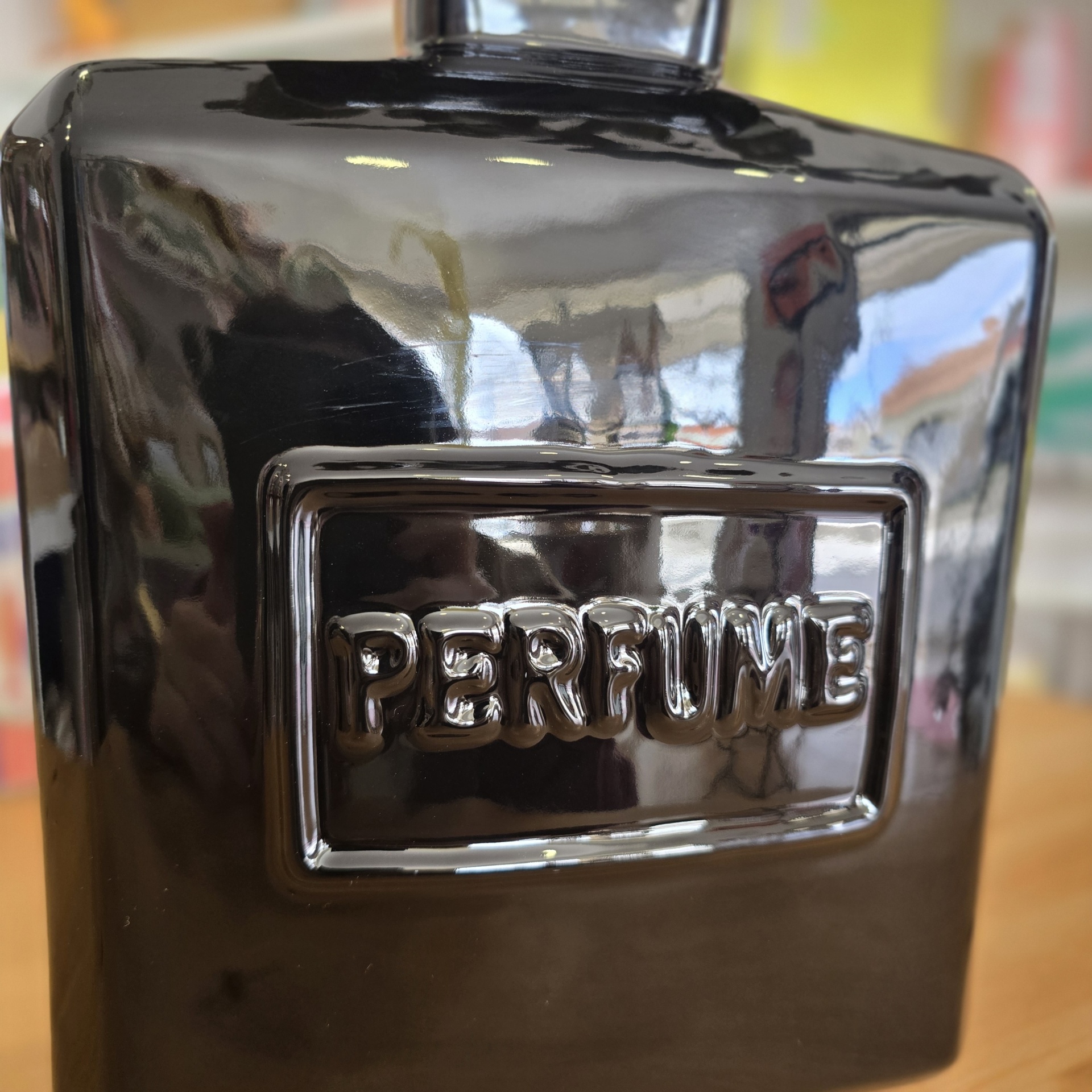 Frasco de perfume preto com a palavra PERFUME em relevo