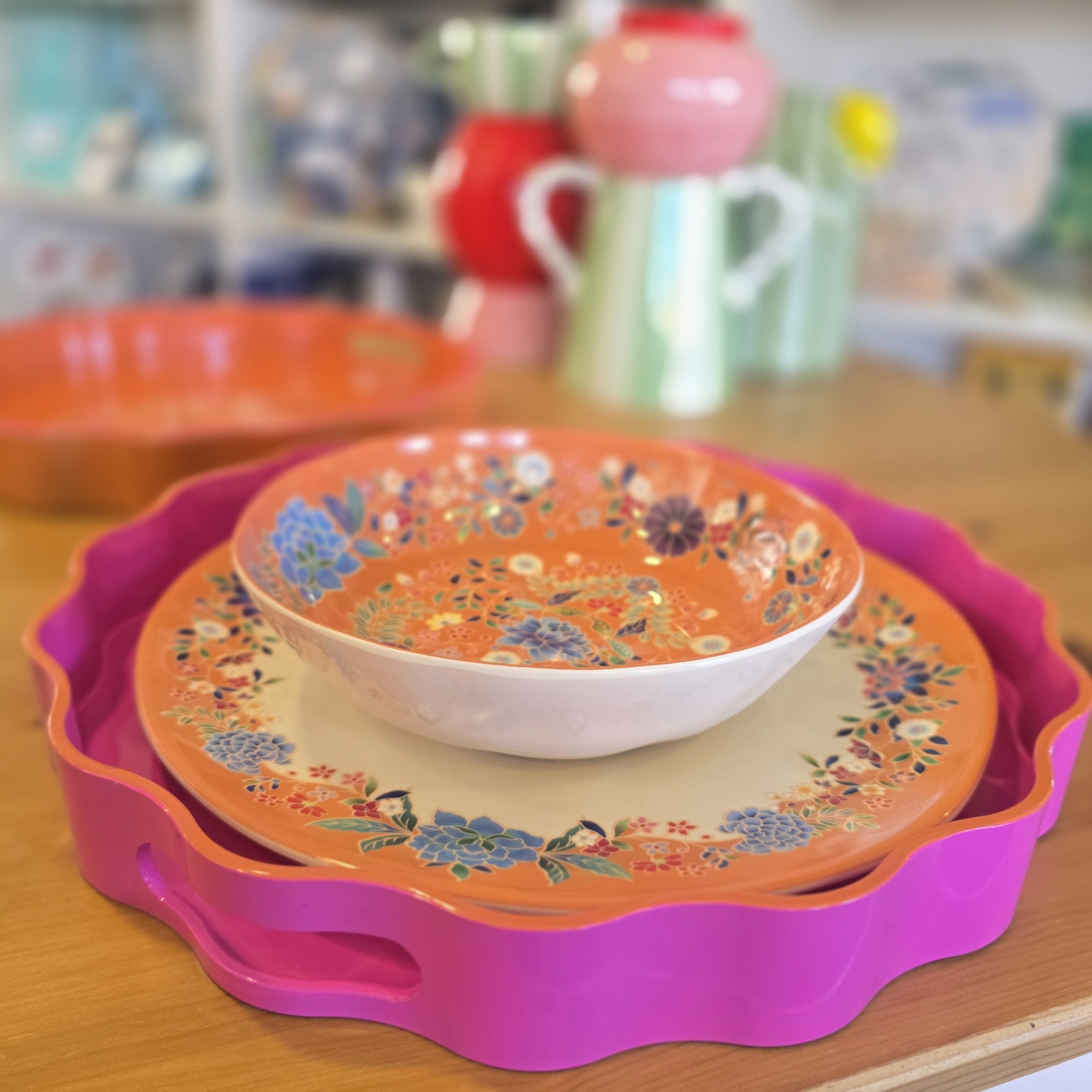 Tabuleiro rosa com pratos florais em cima.