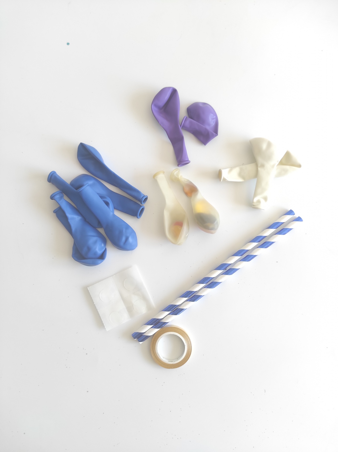 Balões coloridos, palhinhas, fita adesiva e adesivos em fundo branco