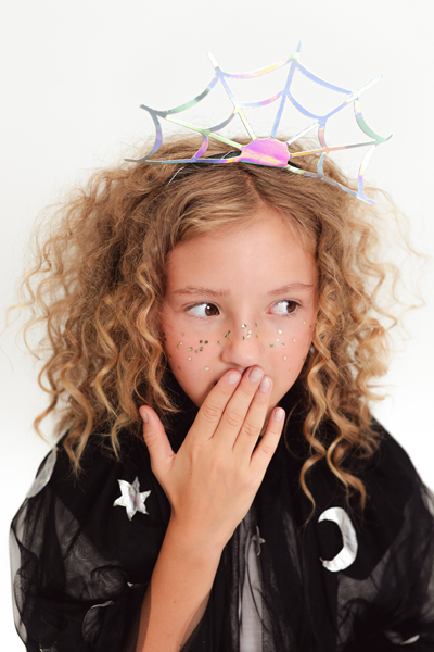 Menina com tiara de teia e capa preta com estrelas e lua