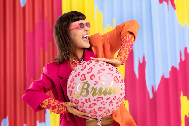 Mulher segura balão rosa com padrão onça e texto Bride em fundo colorido