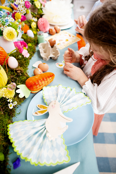 Mesa decorada para festa de Páscoa com pratos, guardanapos em forma de coelho, ovos e flores coloridas