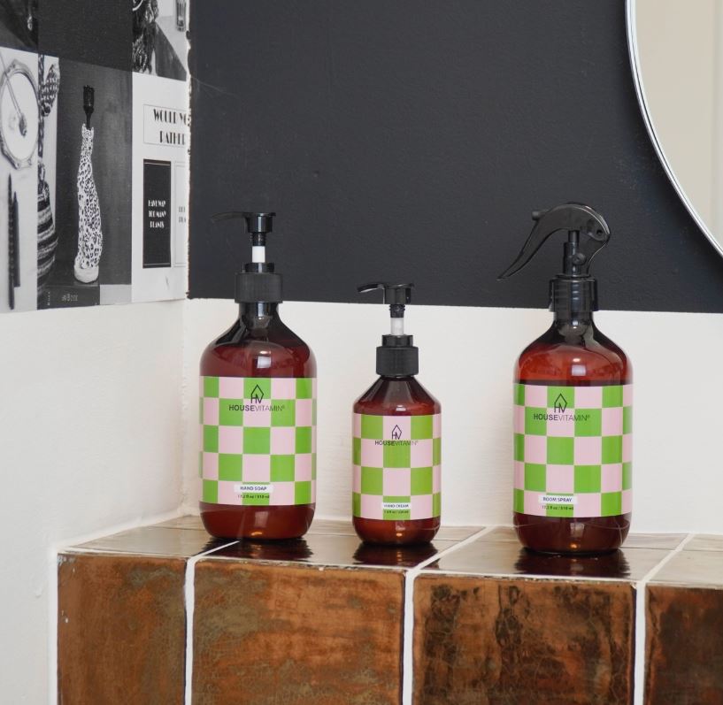 Frascos de sabonete, creme e spray em garrafas âmbar com rótulos quadriculados verdes e brancos