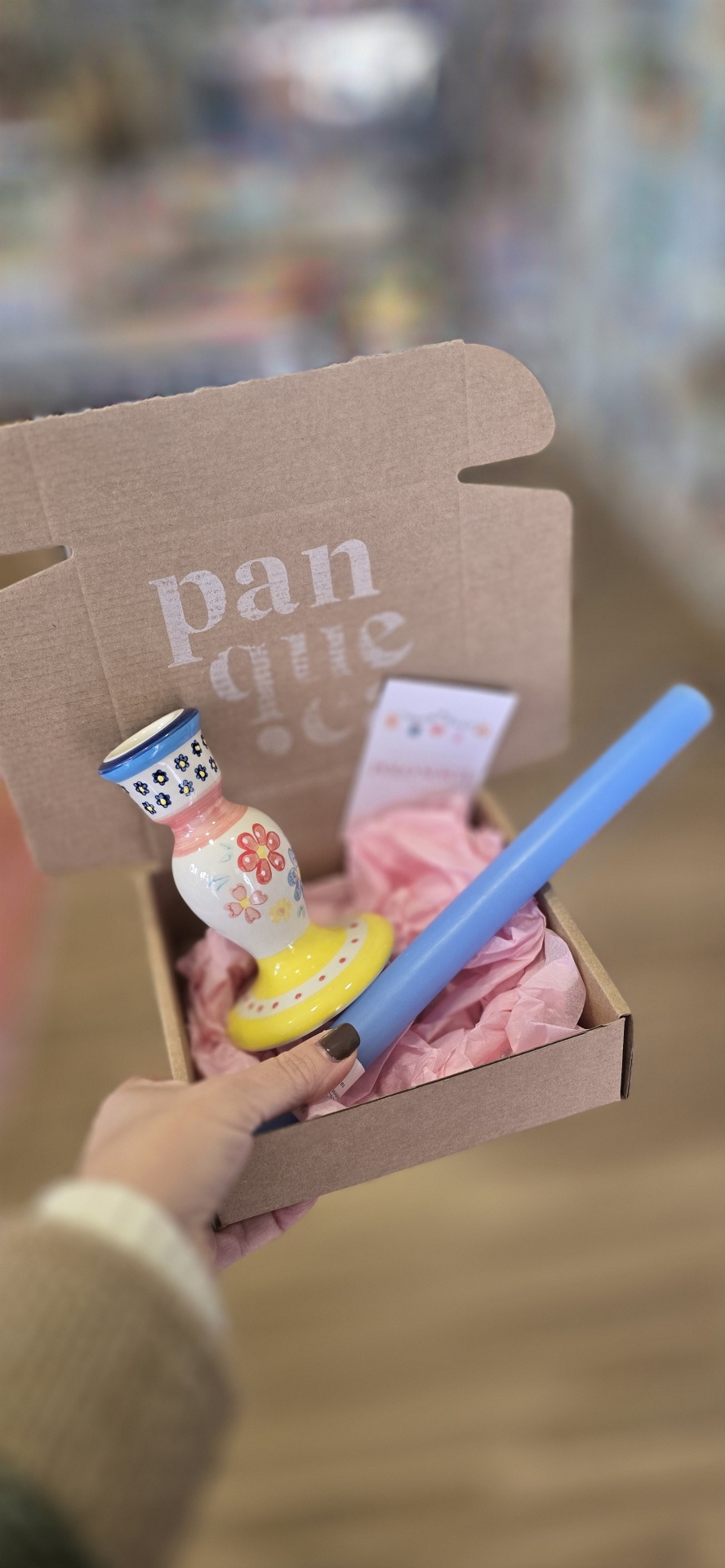 Caixa de cartão com castiçal de cerâmica colorido e vaso azul claro em papel rosa