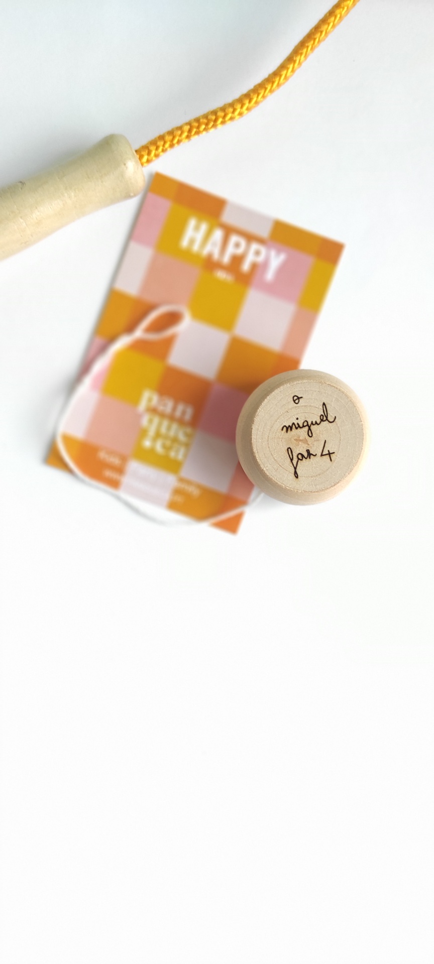 Pega de madeira com corda amarela e cartão colorido com texto HAPPY.