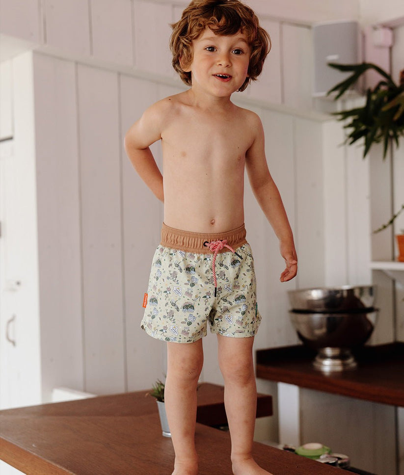 Menino a usar calções florais com cós castanho em ambiente interior