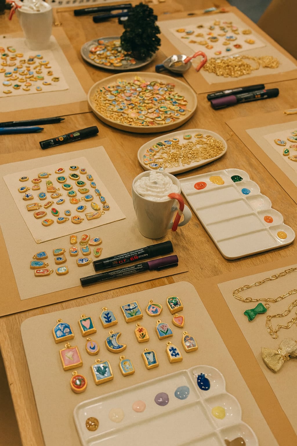 Mesa com bijuteria em miniatura colorida, tintas, marcadores e canecas com chantili