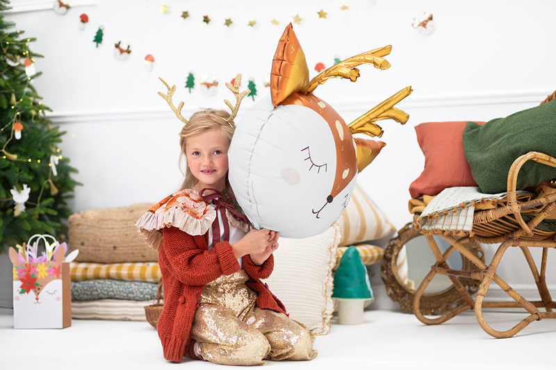 Criança com almofada em forma de rena num cenário natalício