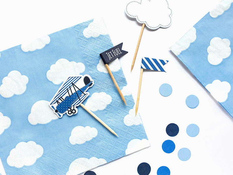 Guardanapos azuis com nuvens brancas e decoração em palitos de madeira com elementos em azul e branco.