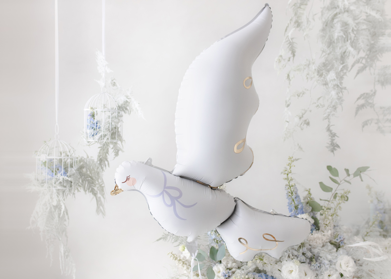 Móvel decorativo em forma de pomba branca com detalhes dourados e lilás suspenso num ambiente com decoração floral