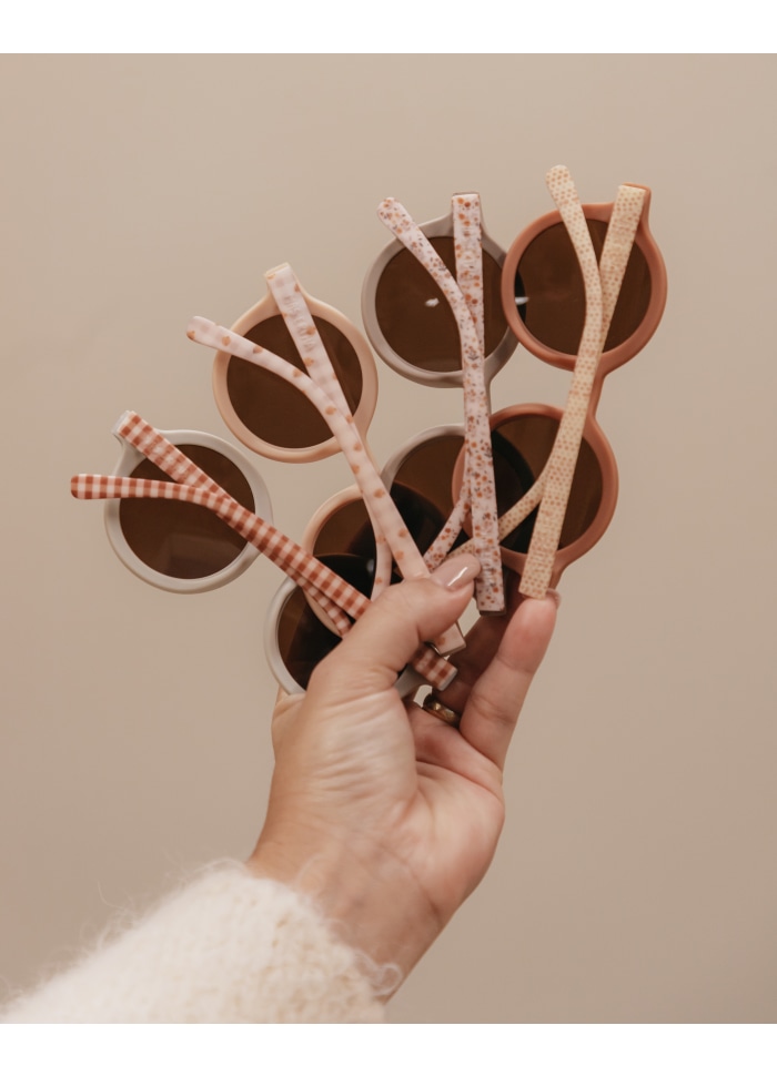 Grampos de cabelo coloridos segurados por uma mão sobre fundo bege