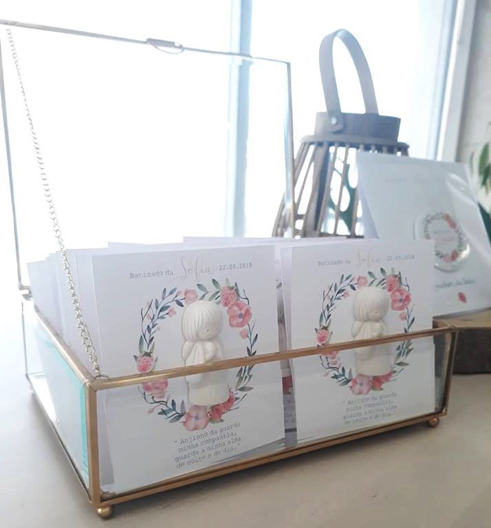 Caixa de vidro dourada com cartões decorativos e figura de anjo