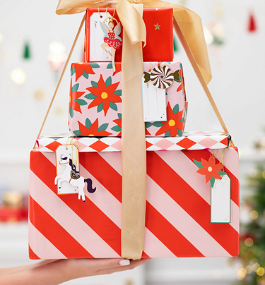 Três caixas de presente coloridas empilhadas com etiquetas e fita dourada