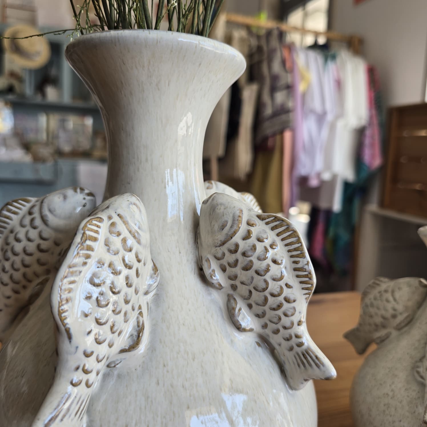 Vaso cerâmico branco com peixes em relevo em interior difuso