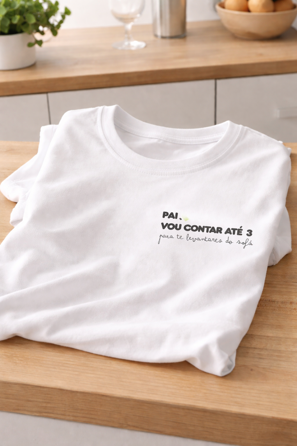 T-shirt branca com texto preto e verde claro dobrada sobre bancada de madeira claro